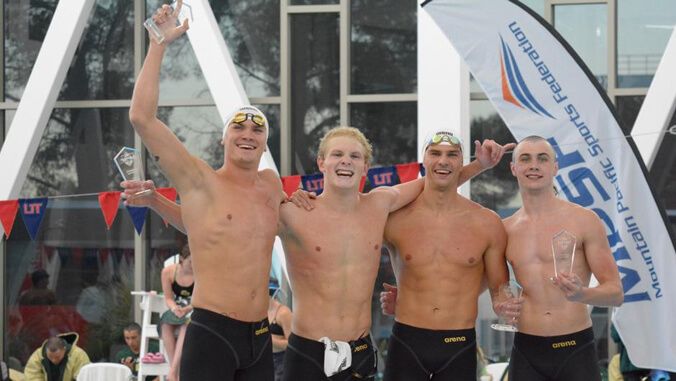 4 swimmers holding a trophy